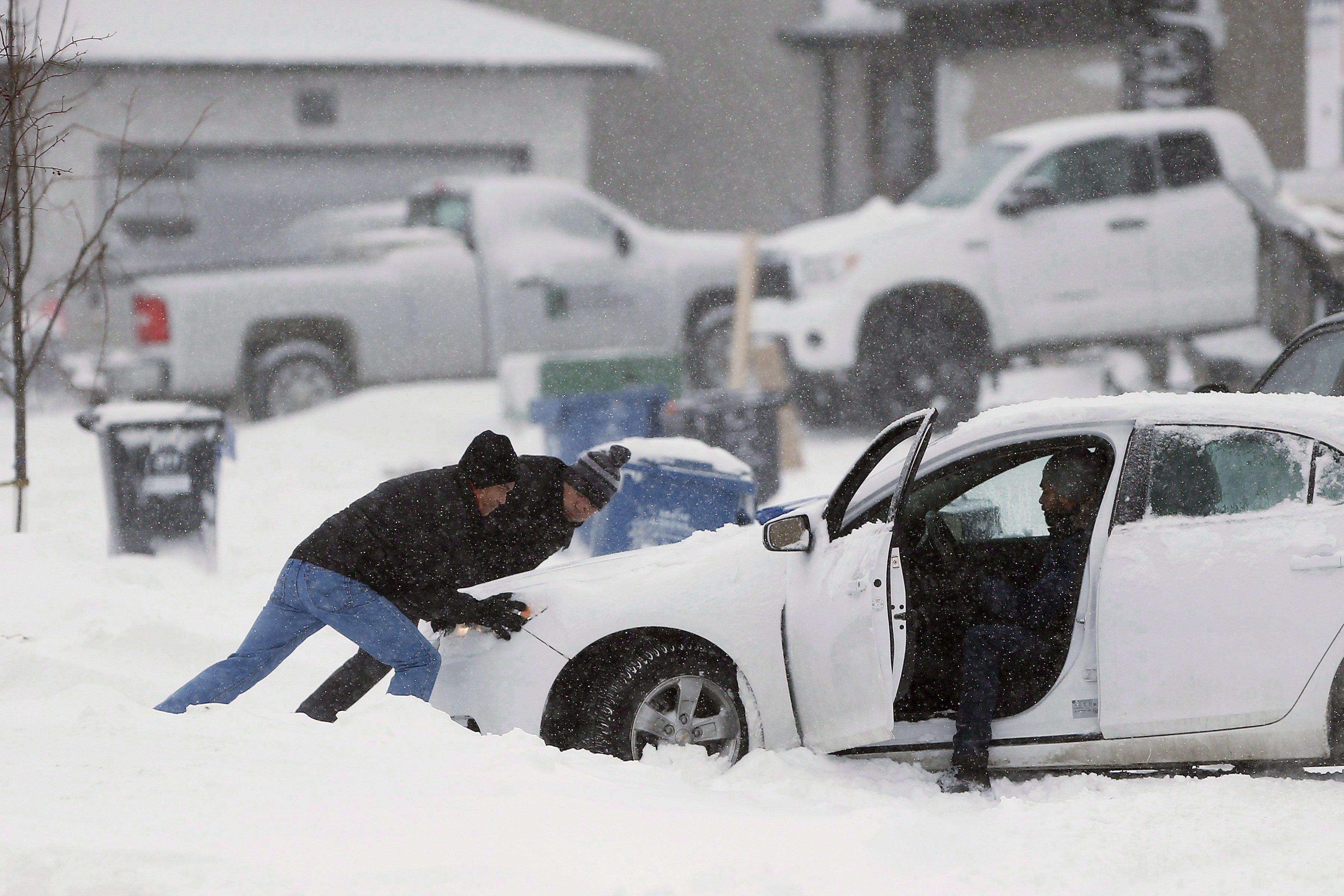 People push a stuck car after two days of snow in Winnipeg, Wednesday, December 7, 2016. It's the dead of winter and despite how ominous that might sound the country's top climatologist says that's actually a good thing. THE CANADIAN PRESS/John Woods